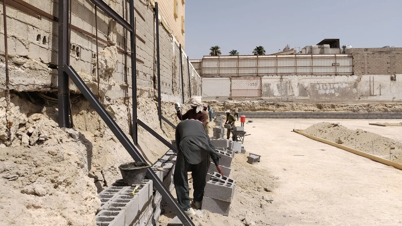 Builder laying concrete blocks along a new retaining wall on site