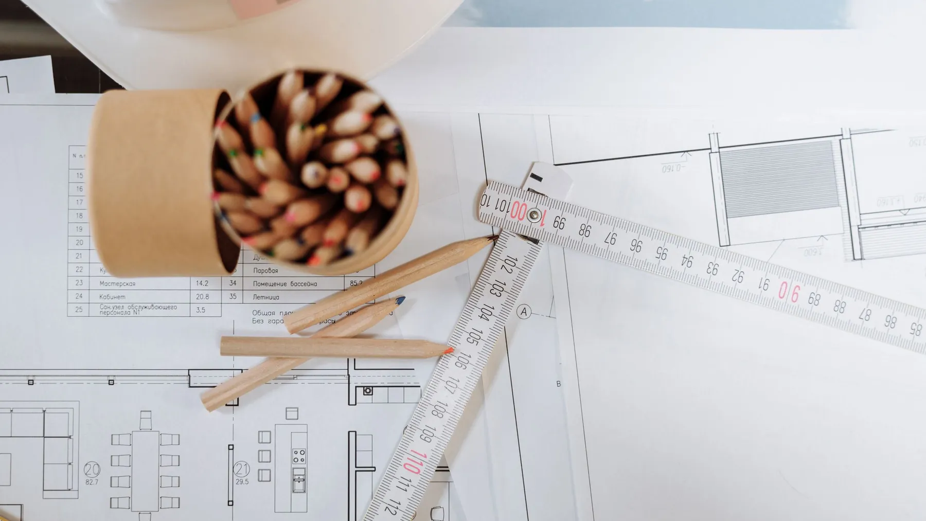Construction drawings with a folding rule and a pot of pencils on a desk