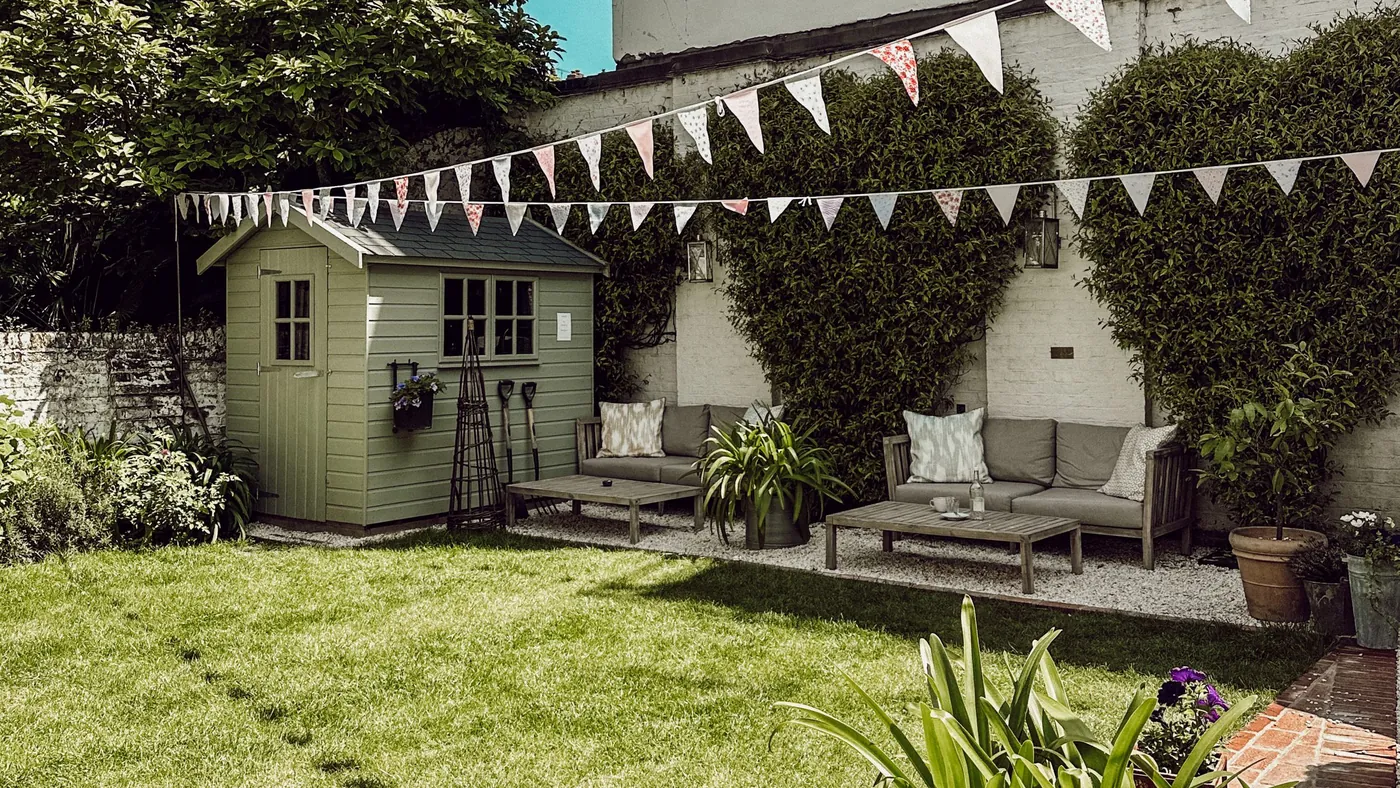 London back garden with a shed, bunting and neighbouring boundary walls