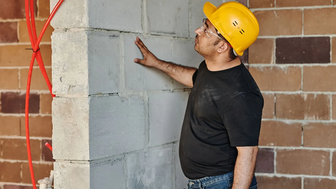 Builder checking a new blockwork wall built up against existing brickwork