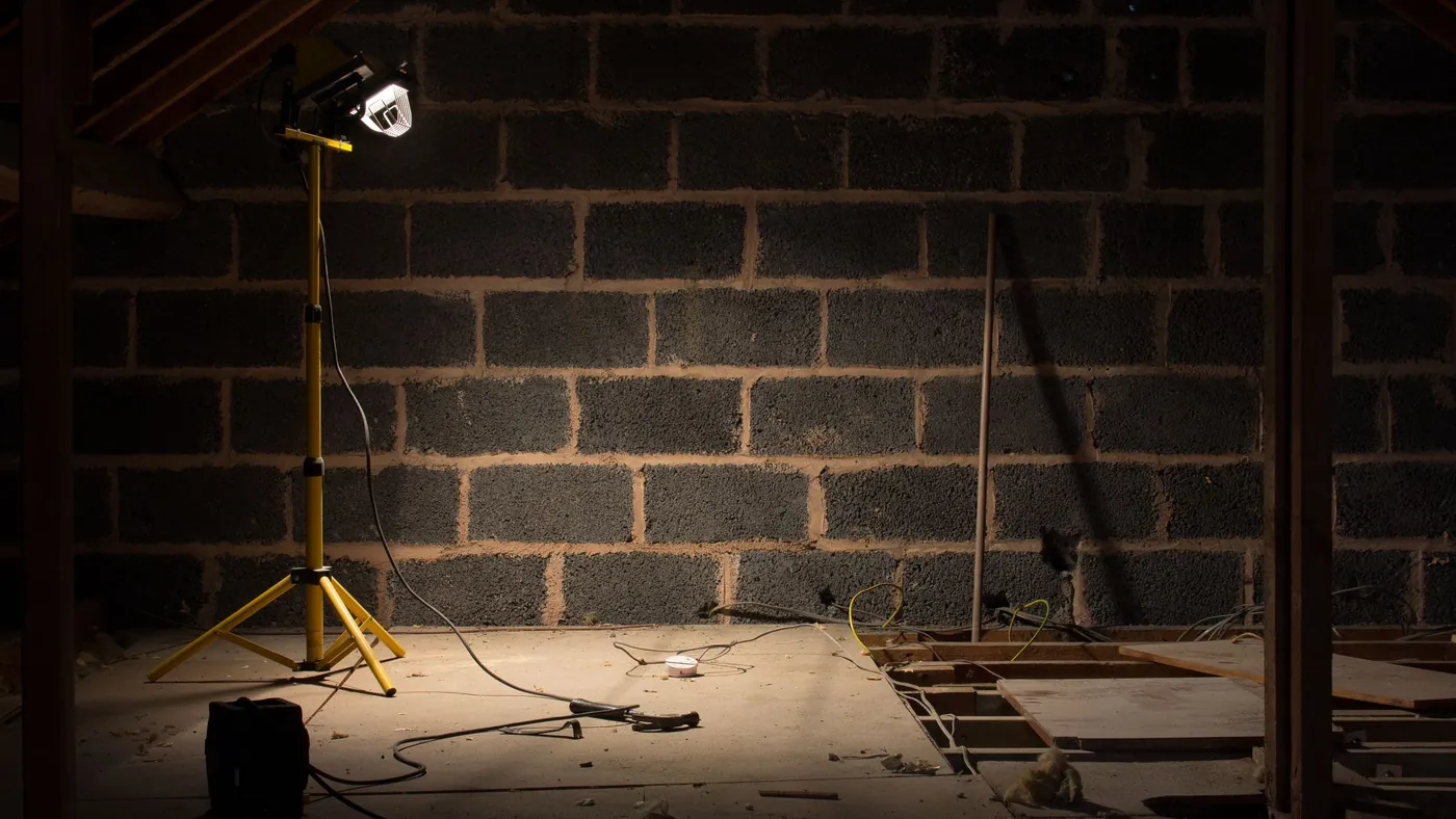 Exposed blockwork party wall in a loft lit by a site lamp